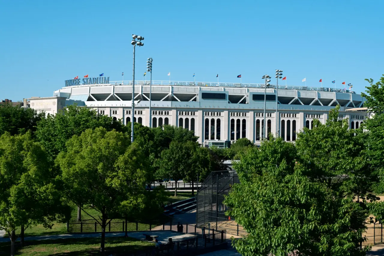 An exterior daytime view of Yankee Stadium in New York surrounded by green trees