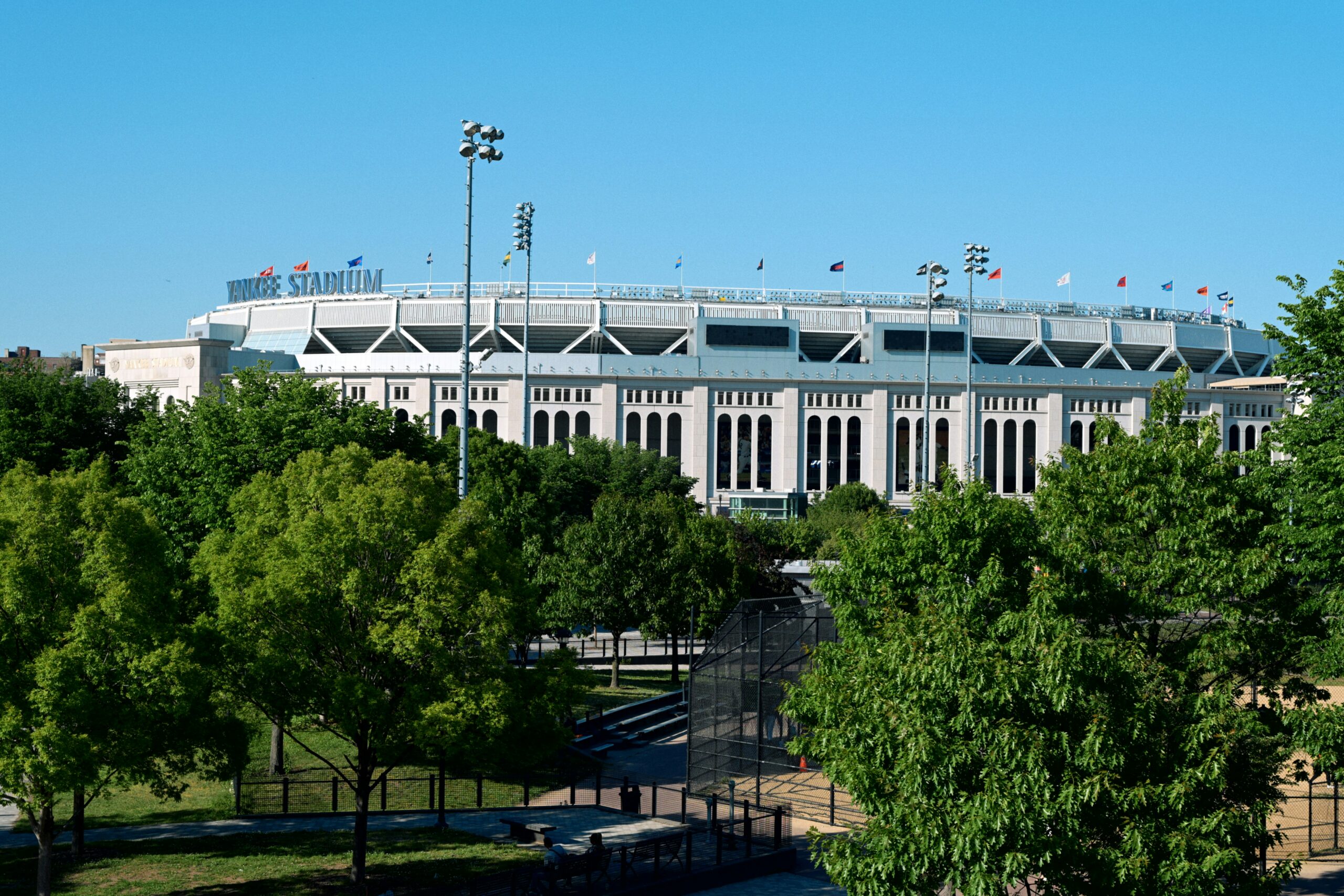 An exterior daytime view of Yankee Stadium in New York surrounded by green trees
